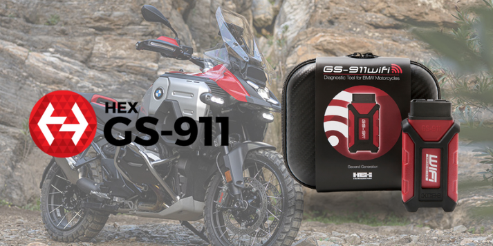A BMW motorcycle parked on rocky terrain with a GS-911 diagnostic tool and its packaging displayed in the foreground, featuring the HEX logo.